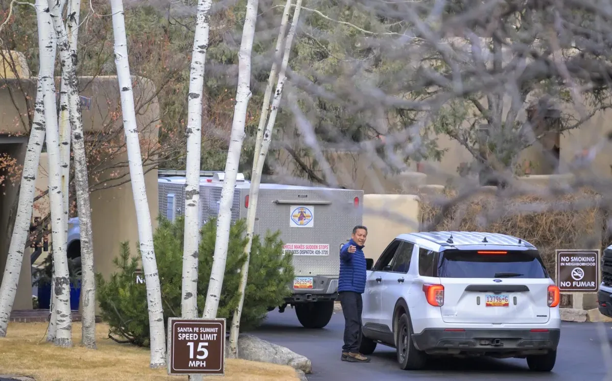 محقق يقف بجانب سيارة في موقع حادث وفاة جين هاكمان وزوجته في نيو مكسيكو، مع لافتة تحدد سرعة القيادة.