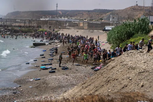 حشد كبير من المهاجرين المغاربة على شاطئ سبتة يحاولون عبور الحدود الإسبانية وسط موجة هجرة جديدة وتوتر أمني.
