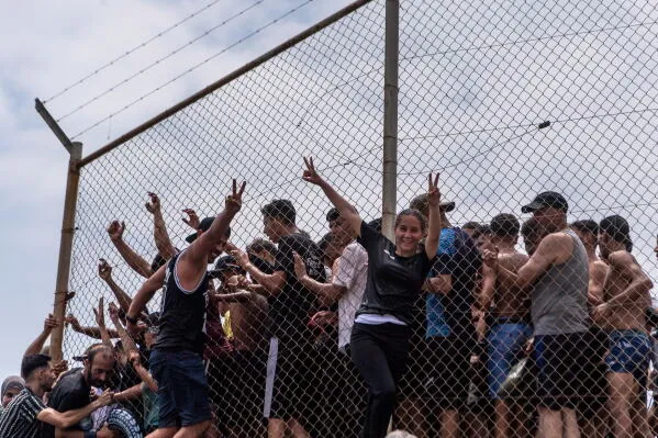 مهاجرون شباب يحتشدون عند سياج حدودي في سبتة الإسبانية، في ظل موجة هجرة كبيرة من المغرب ومحاولات عبور الحدود.