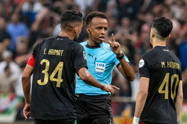 عمر أرتان، الحكم الصومالي، يتحدث مع لاعبين خلال مباراة، معبرًا عن دوره التاريخي كأول حكم صومالي في كأس الأمم الأفريقية.