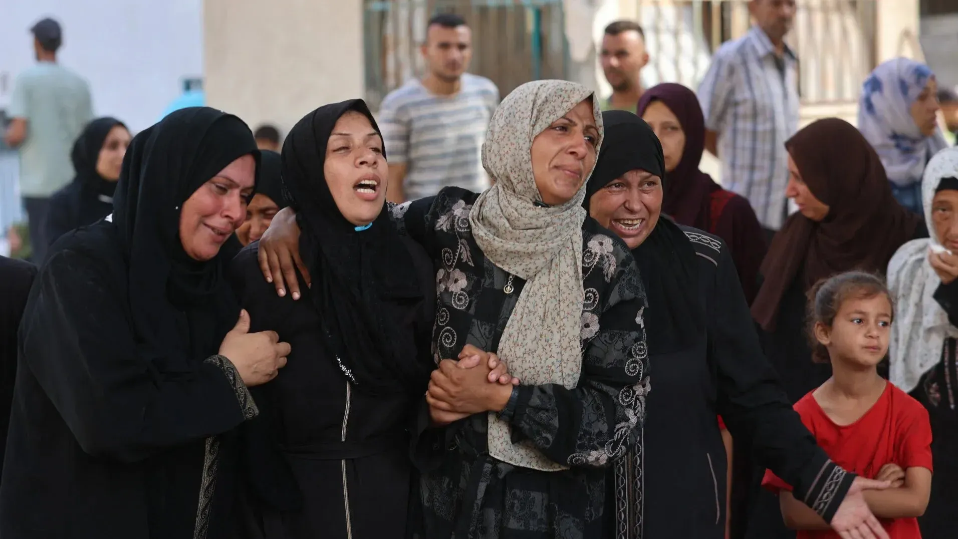 نساء فلسطينيات يرتدين الحجاب، يعبرن عن حزنهن في تجمع، بينما تظهر ملامح الألم والقلق في وجوههن، وسط أجواء من التوتر.