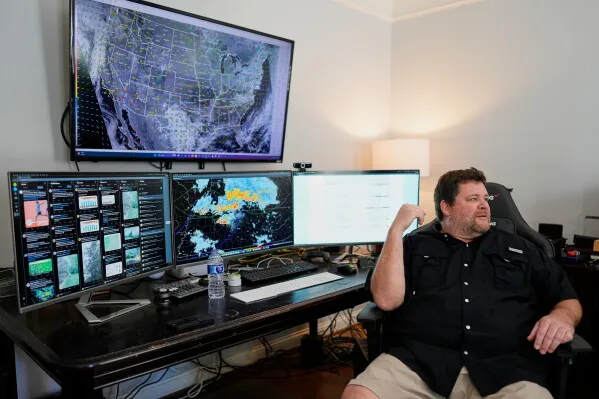 رجل يجلس أمام عدة شاشات تعرض خرائط الطقس والرادار في غرفة، يعكس جهود متطوعي Nashville Severe Weather في تقديم نشرات الطقس المحلية المباشرة.
