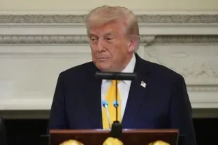 صورة لدونالد ترامب يتحدث في البيت الأبيض، مع التركيز على قضايا تنظيم الذكاء الاصطناعي وتأثيرها على الابتكار.