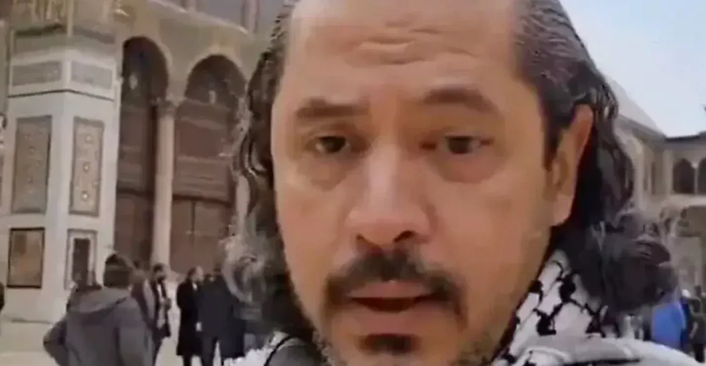 عبد الرحمن يوسف القرضاوي، شاعر وناشط سياسي، يظهر في المسجد الأموي بدمشق، يرتدي كوفية فلسطينية، مع خلفية تاريخية.