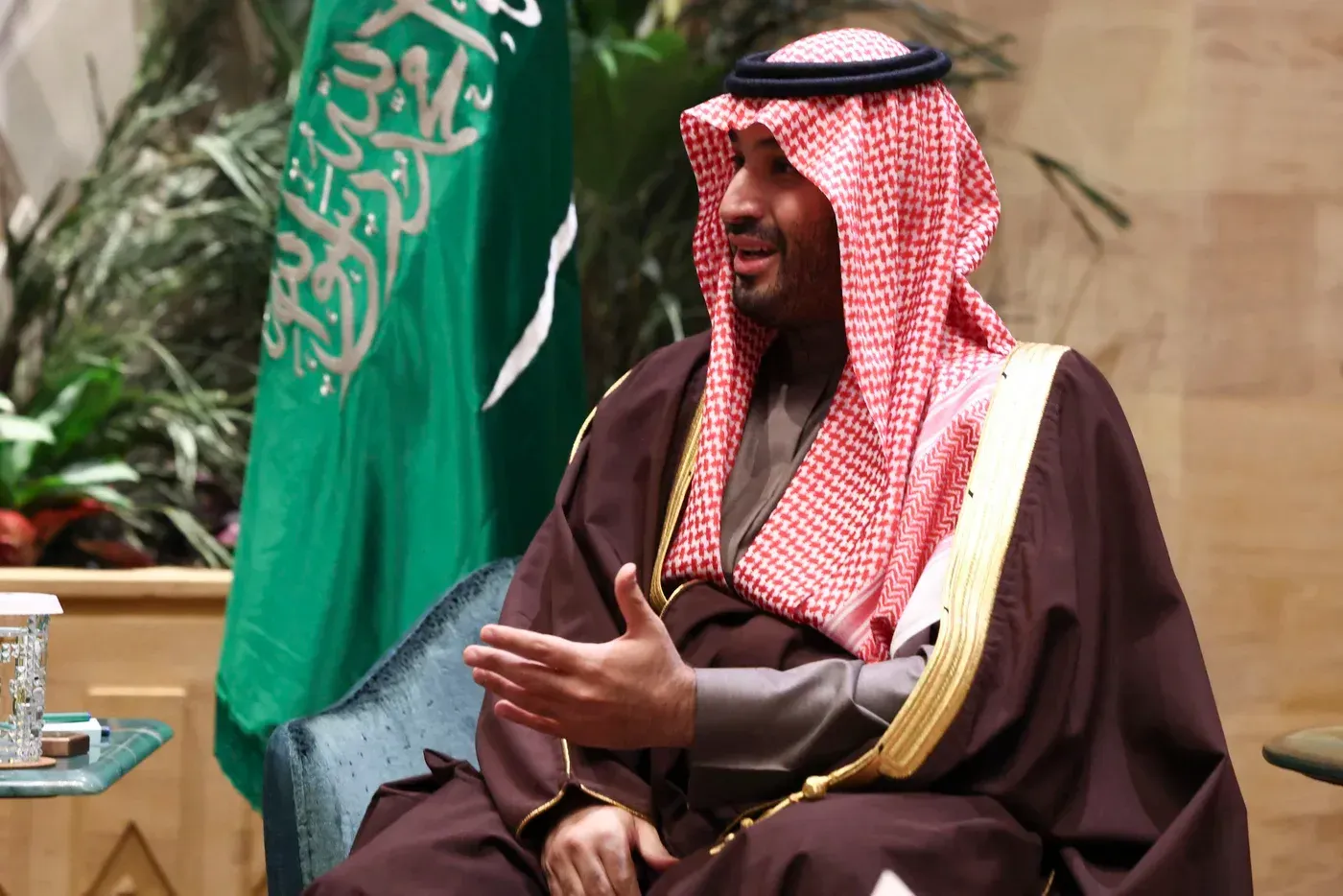 ولي العهد السعودي محمد بن سلمان يتحدث في مناسبة رسمية، مع العلم السعودي خلفه، يعكس الأبعاد السياسية والاقتصادية للمملكة.