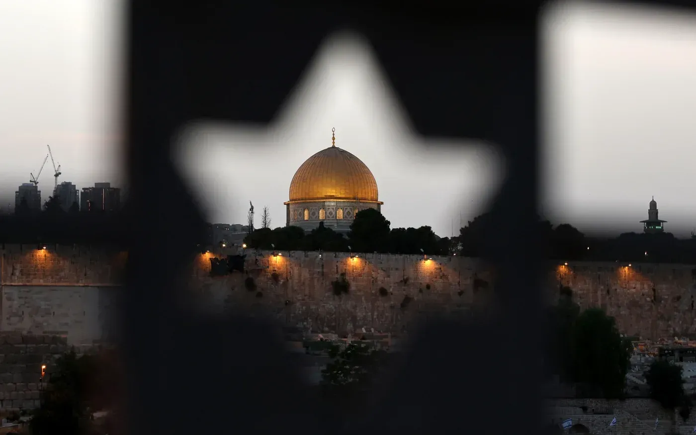 صورة تظهر قبة الصخرة في المسجد الأقصى، محاطة بأضواء المساء، مما يعكس التوترات الحالية حول هذا الموقع المقدس.