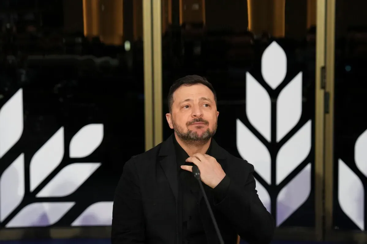 الرئيس الأوكراني فولوديمير زيلينسكي يتحدث في مؤتمر، مع خلفية تظهر شعارات تمثل الدعم الأوروبي لأوكرانيا في أزمتها المالية.