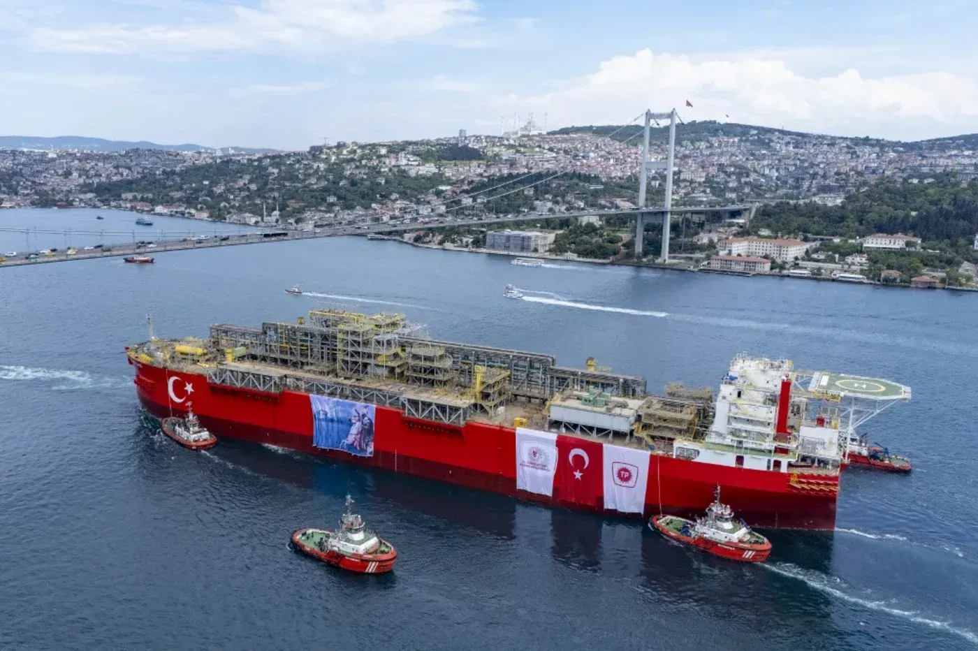 سفينة الغاز التركية في مضيق البوسفور، محاطة بزوارق صغيرة، مع خلفية للمدينة والجبال، تعكس جهود تركيا في تأمين إمدادات الطاقة.