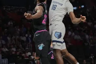 لاعب من فريق ميامي هيت يتنافس مع لاعب من ممفيس جريزليز في مباراة كرة السلة، مع تركيز على الحركة الديناميكية بين اللاعبين.