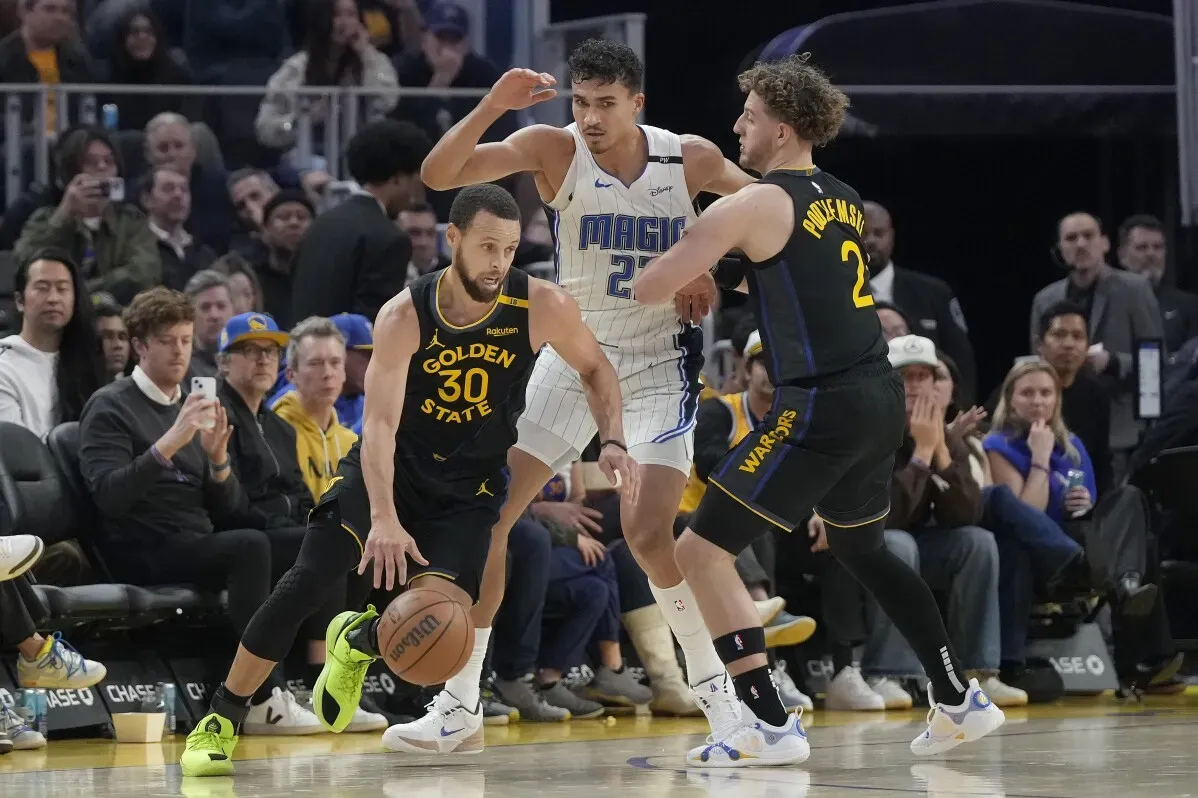 ستيفن كاري يت dribble الكرة خلال مباراة غولدن ستيت ووريورز ضد أورلاندو ماجيك، مع وجود لاعبين آخرين في الخلفية.
