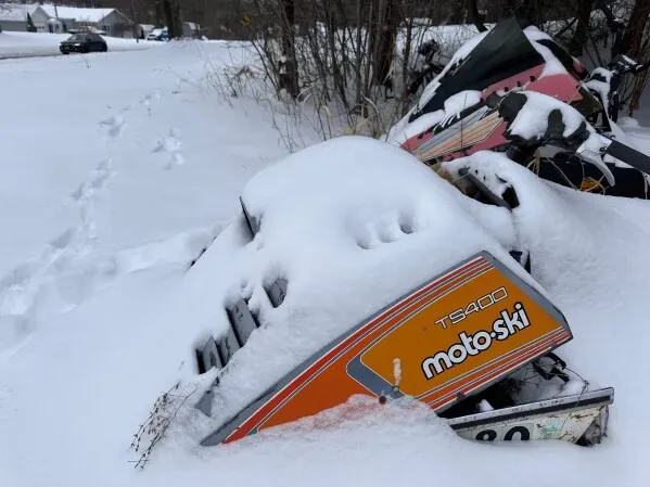 تظهر الصورة مركبة ثلجية مغطاة بالثلوج في منطقة خارجية، مما يعكس تأثير العاصفة الثلجية على السفر في شمال شرق الولايات المتحدة.
