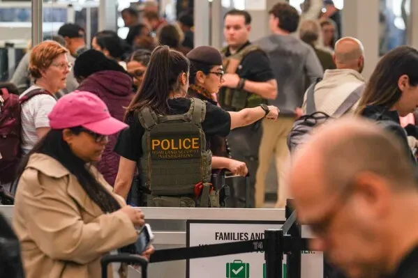 ازدحام في مطار مع وجود ضباط أمن يرتدون زي الشرطة، حيث ينتظر المسافرون في طوابير طويلة خلال أوقات الذروة.