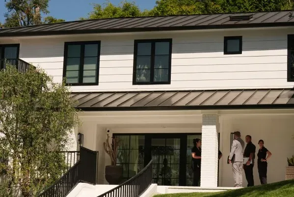 منزل حديث في بيفرلي هيلز مع مجموعة من الأشخاص يتحدثون أمام المدخل، في سياق قضية إيفانا أورتيز المتعلقة بإطلاق النار.