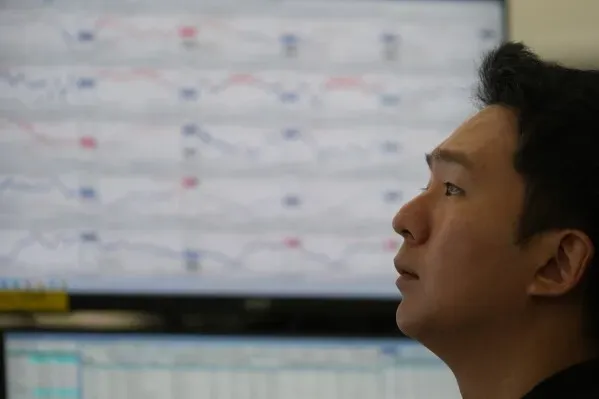 متداول يراقب شاشات الأسهم في سوق المال، مع تباين أداء الأسهم العالمية وتأثير انخفاض أسهم شركات الذكاء الاصطناعي.