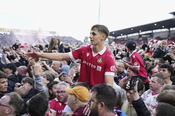 احتفال مشجعو ريكسهام بفوز فريقهم 3-0 على تشارلتون، حيث يتفاعل لاعب مع الجماهير في ملعب Racecourse Ground.