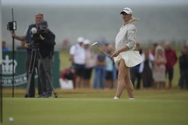 ميو ياماشيتا تسدد الكرة على الخضراء في بطولة بريطانيا المفتوحة للسيدات، مع وجود مشجعين والكاميرات في الخلفية.