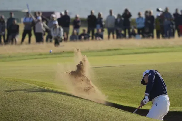 لاعبة غولف تسدد الكرة من مخبأ رملية، بينما يتجمع الجمهور في الخلفية لمتابعة بطولة بريطانيا المفتوحة للسيدات.