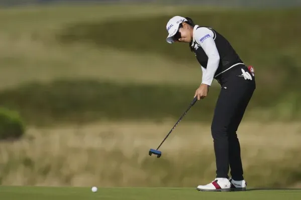 ميو ياماشيتا تسدد كرة الغولف في بطولة بريطانيا المفتوحة للسيدات، مع خلفية خضراء، وسط تحديات صعبة في الجولة.