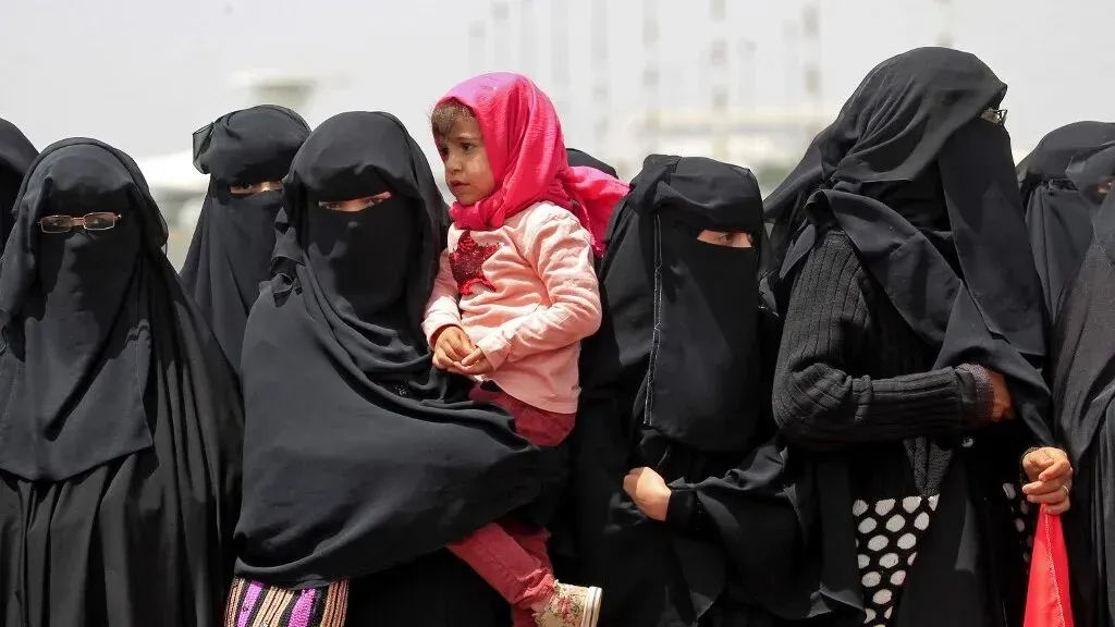 نساء يمنيات يرتدين الحجاب، مع طفلة تحملها إحداهن، يظهرن في تجمع يعكس التحديات الإنسانية التي يواجهنها في ظل أزمة التمويل.