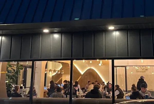 مقهى يمني مزدحم في الليل، حيث يجتمع الزبائن لتجربة القهوة اليمنية الأصيلة، مع أجواء مريحة وتصميم داخلي عصري.
