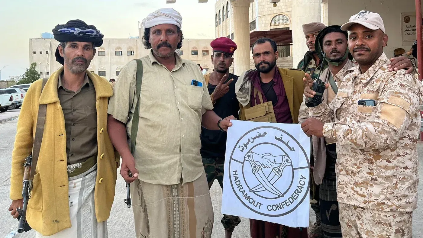 مجموعة من الرجال اليمنيين يحملون علم "اتحاد حضرموت" في المكلا، يعكسون التوترات السياسية والعسكرية في المنطقة بعد الضربة السعودية.