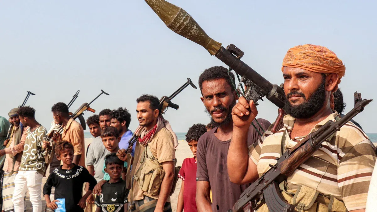 مسلحون حوثيون يحملون أسلحة ثقيلة وخفيفة في صف على الساحل، في سياق إعلان الحوثيين فرض حصار بحري على السعودية في البحر الأحمر.