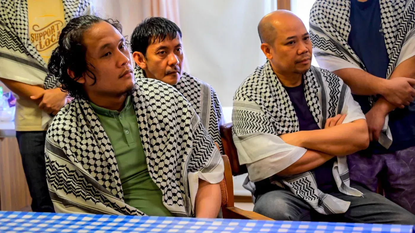 أفراد طاقم السفينة "جالاكسي ليدر" بعد الإفراج عنهم، يرتدون الشال الفلسطيني، محتشدين في غرفة.