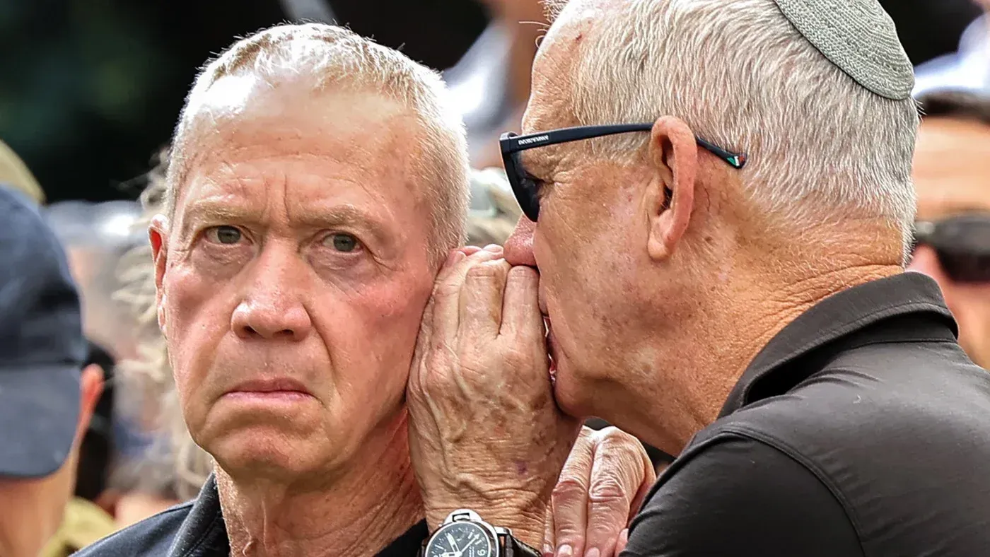 وزير الدفاع الإسرائيلي السابق يوآف غالانت يتحدث بجدية مع مسؤول آخر، مع تعبيرات وجه تعكس القلق بشأن الاحتجاجات في إيران.