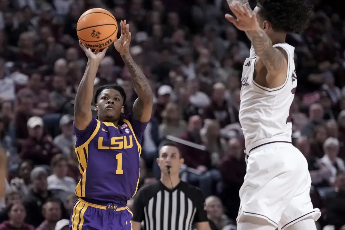 لاعب من فريق LSU يسدد كرة سلة بينما يحاول مدافع من فريق تكساس إيه آند إم اعتراض التسديدة في مباراة مثيرة.