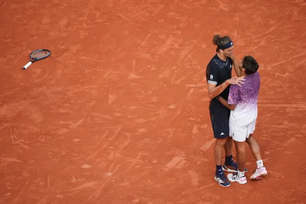 احتفال Alexander Zverev بفوزه ببطولة Roland Garros مع Flavio Cobolli بعد مباراة مثيرة، مع وجود مضرب ملقى على الأرض.